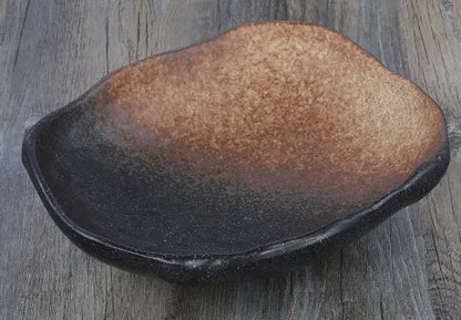 Japanese style irregular shaped ceramic sashimi bowl with floral decoration on table.