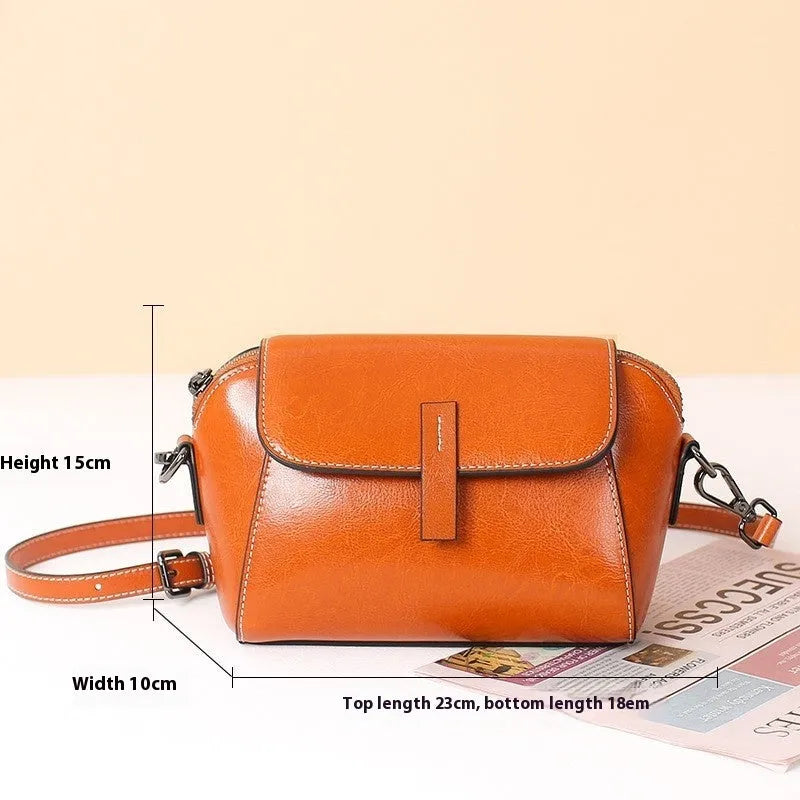 Women's brown shell-shaped genuine leather messenger bag with a single shoulder strap and visible stitching.