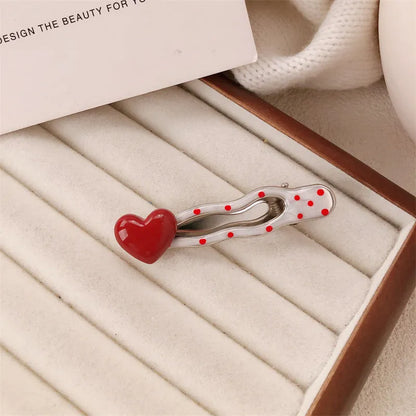 Red plastic hair clip with a 3D love heart and dots on a willow leaf-shaped base.