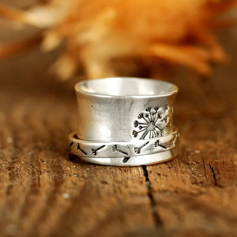 Silver-coloured rotating flower ring on finger showing adjustable floral element