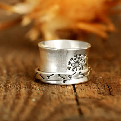 Silver-coloured rotating flower ring on finger showing adjustable floral element