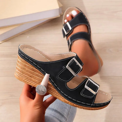Women's creamy-white wedge slippers with an outer belt buckle and a rubber sole.