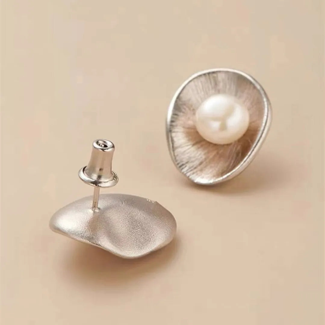 A pair of gold-coloured geometric sterling silver stud earrings with white pearl accents on a white background.