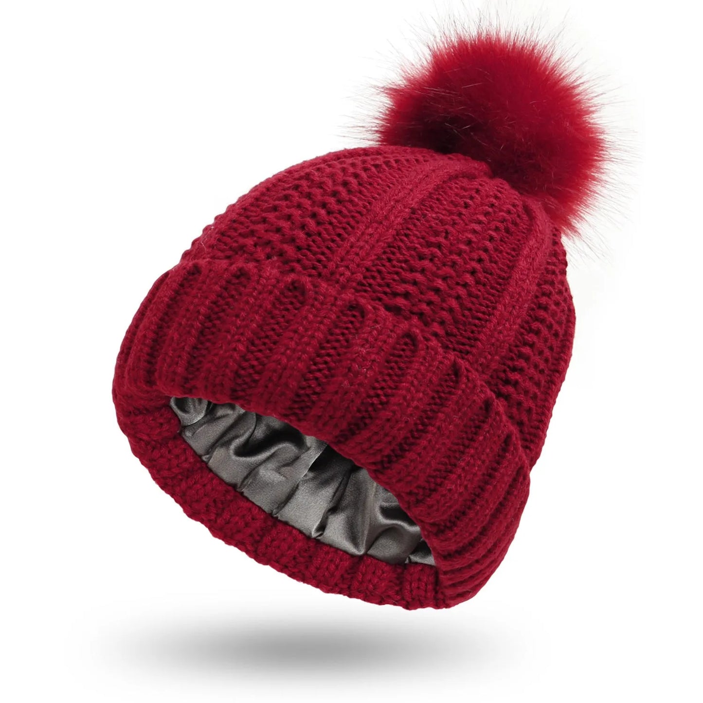 Wool knit beanie hat for women with faux fur pom pom and satin lining, shown in a wine red colour.