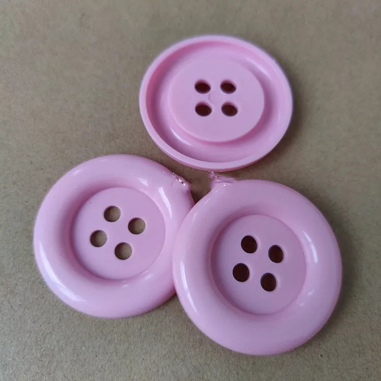 Assorted oversized round plastic buttons in various colours showing four-hole sew-through design.
