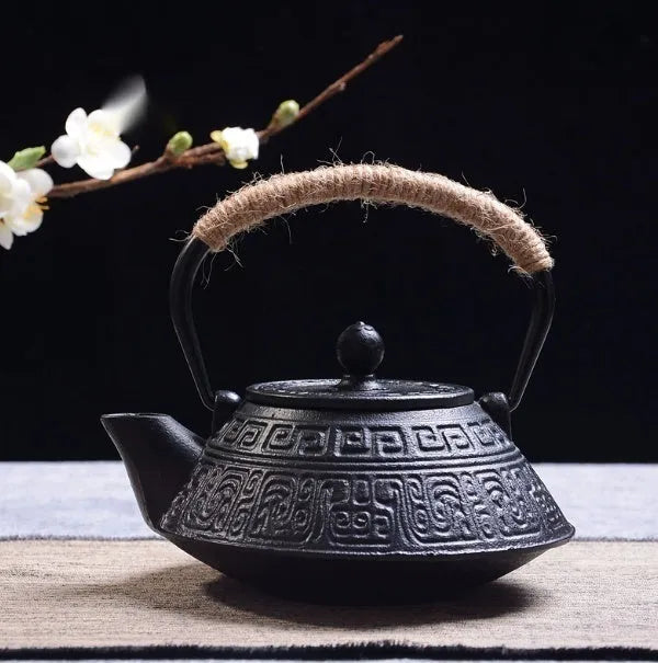 Japanese-style cast iron teapot with lid on a hob, shown in a bronze finish.
