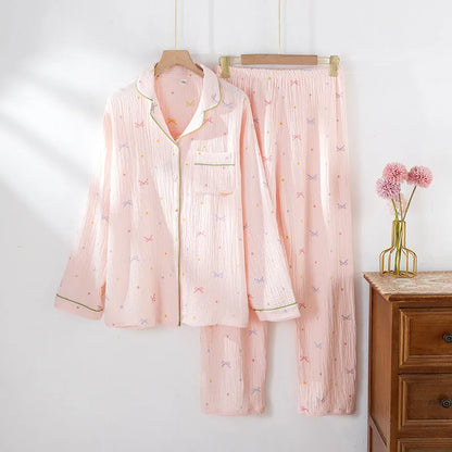Women's pink cotton long sleeve pajama set with trousers on a hanger.