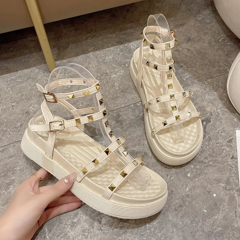 Women's Roman-style flat sandals with round toe, rivet platform, ankle buckle, PU upper, rubber sole, beige or black.