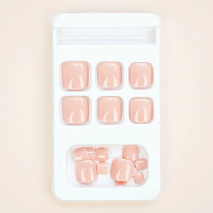 Fashion Personality toe nail stickers in skin colour with design, next to tube of adhesive glue on a flat surface.