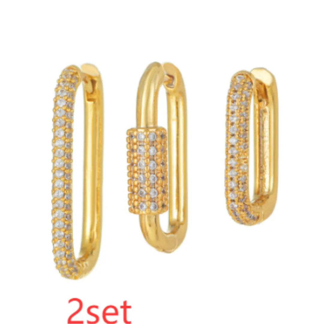 Three geometric copper ear clips with micro inlaid zircon in gold and white tones on a grey background.