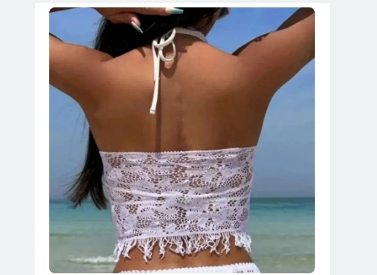 Women's white two-piece swimsuit with lace bikini top and tassel skirt on beach