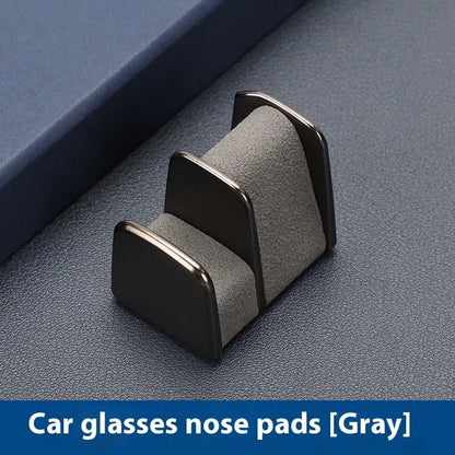 Green zinc alloy and leather glasses clip holder attached to a car dashboard, holding sunglasses.