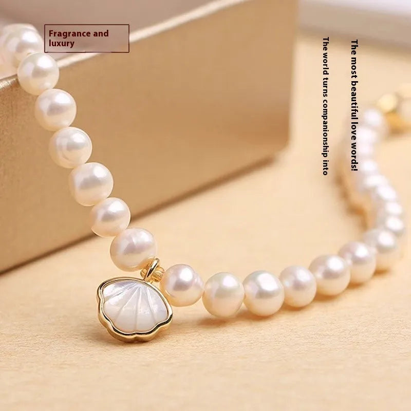 Women's freshwater pearl bracelet with fan-shell centrepiece on a 16cm elastic string or extension chain.