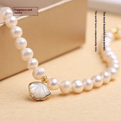 Women's freshwater pearl bracelet with fan-shell centrepiece on a 16cm elastic string or extension chain.