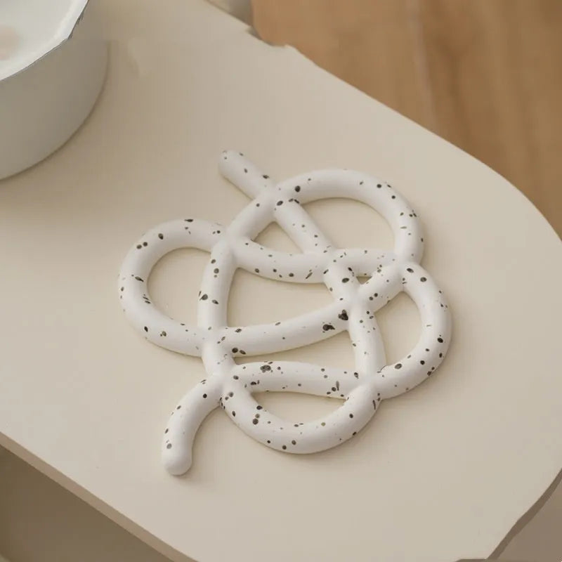 Ceramic heat-proof mat in irregular shape on dining table, protecting surface from hot pot