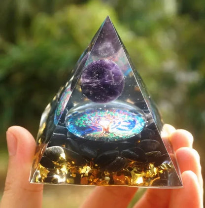 A small 6cm clear epoxy resin pyramid ornament containing pieces of natural crystal gravel on a flat surface.