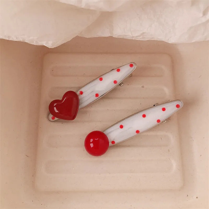 Red plastic hair clip with a 3D love heart and dots on a willow leaf-shaped base.