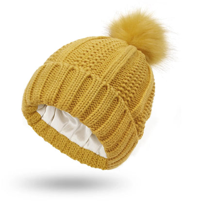 Wool knit beanie hat for women with faux fur pom pom and satin lining, shown in a wine red colour.