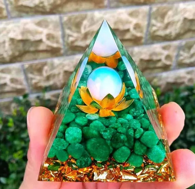 A small 6cm clear epoxy resin pyramid ornament containing pieces of natural crystal gravel on a flat surface.