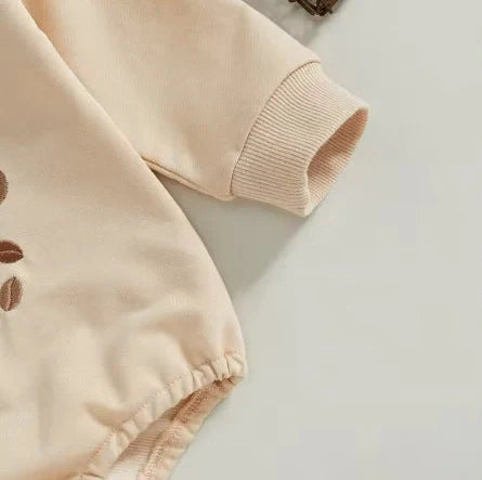 Apricot coloured infant jumpsuit with embroidered alphabet detailing and long sleeves
