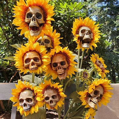A group of skull-shaped sunflower ornaments arranged in a Halloween-themed outdoor display