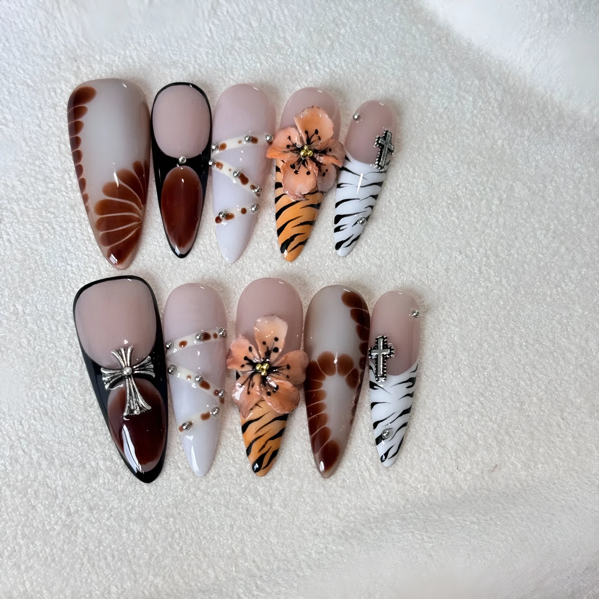 Handmade leopard print gel nail wraps on a manicured hand, showing cross and floral design details.