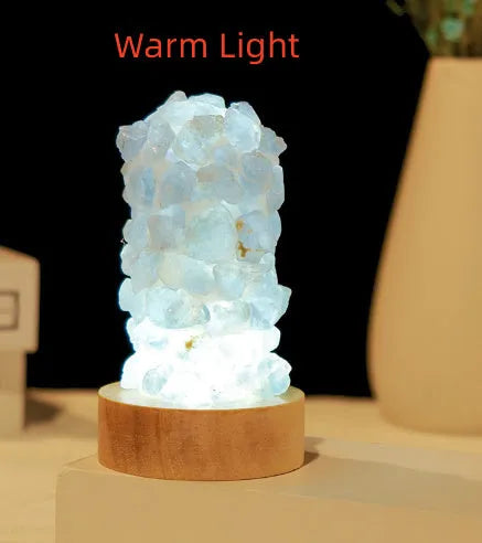 Miniature amethyst crystal tooth flower night light glowing with warm light on a wooden surface.