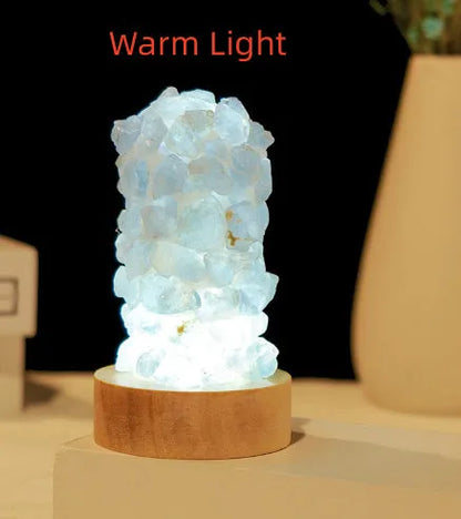 Miniature amethyst crystal tooth flower night light glowing with warm light on a wooden surface.
