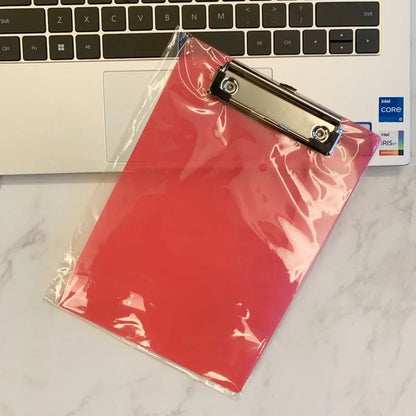 Transparent A4 writing board pad with metal flat clip in blue, alongside A5 size in red on a desk.
