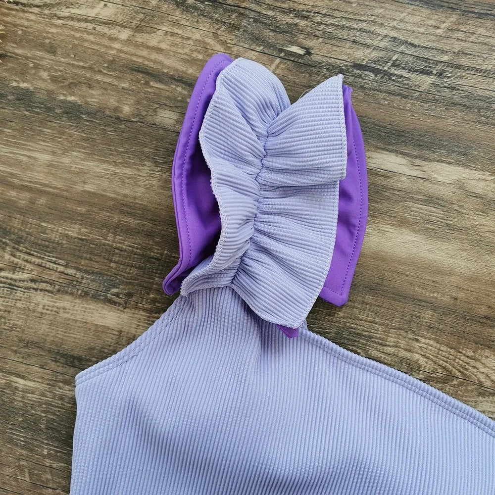 A woman's solid colour one-piece swimsuit with a single-shoulder suspender tube top design.