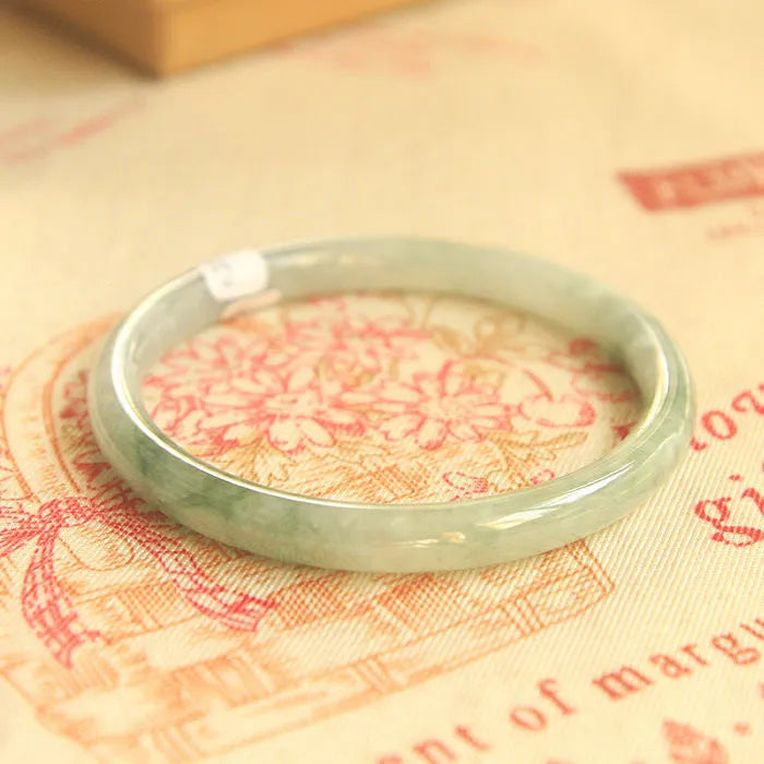 Green geometric jade waxy bracelet on a wrist, showing its 10mm thickness and Chinese style.