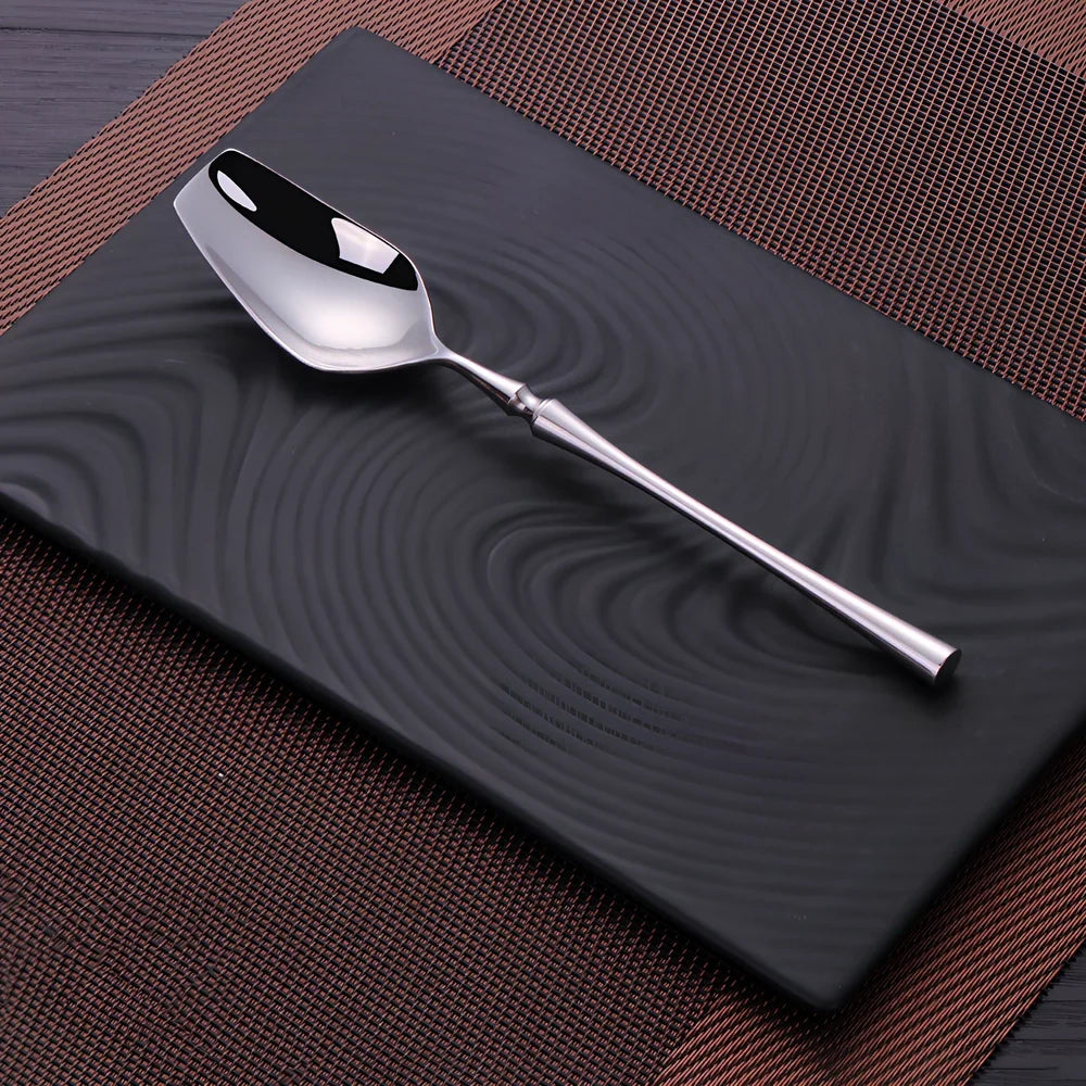 Four-piece stainless steel cutlery set showing main knife, fork, spoon, and teaspoon with mirror finish