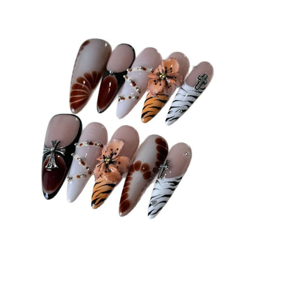 Handmade leopard print false nails with cross and flower designs on a white background, showing long wear-resistant tips.