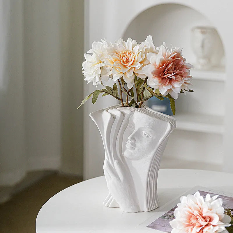 White ceramic book stand holding an open book at an angle, with a wire page holder in use.