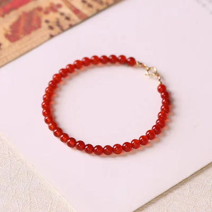 Slim red agate bead bracelet for women on a wrist, classic minimalist jewellery style.