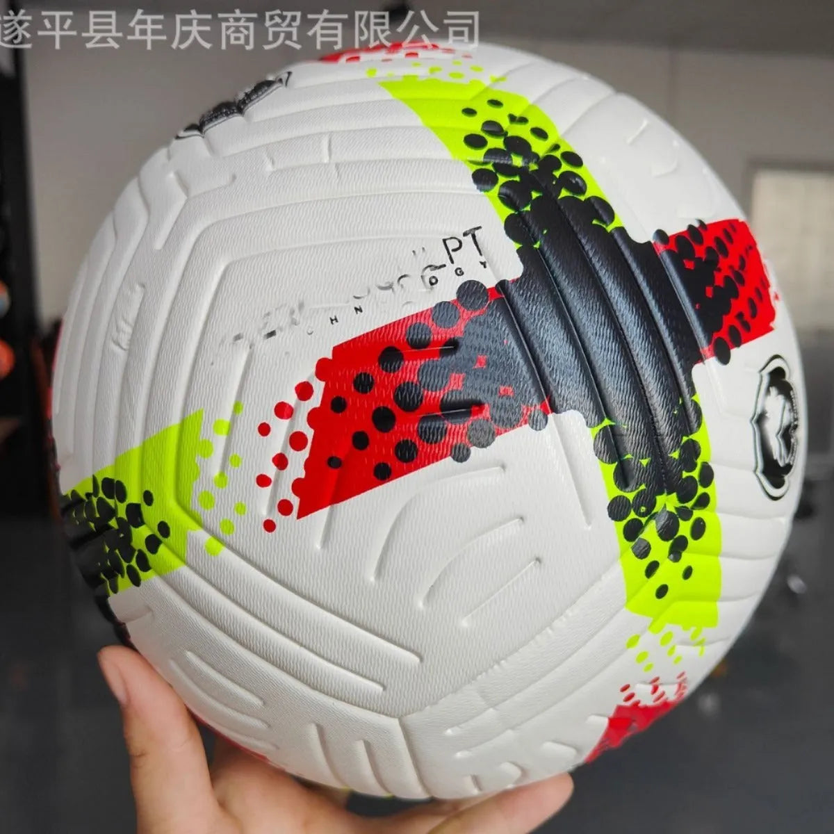 Fluorescent green Size 5 football with seamless patch construction on a green pitch.
