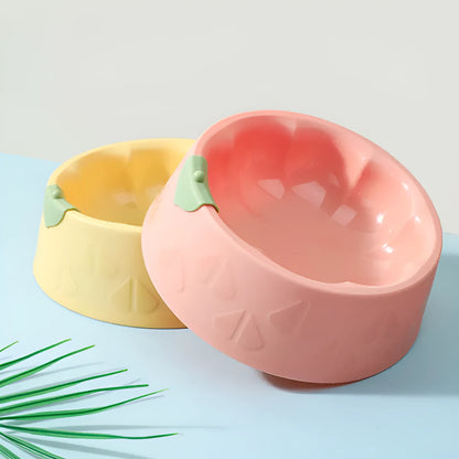 Green plastic double pet bowl with two compartments for food and water on a flat surface.