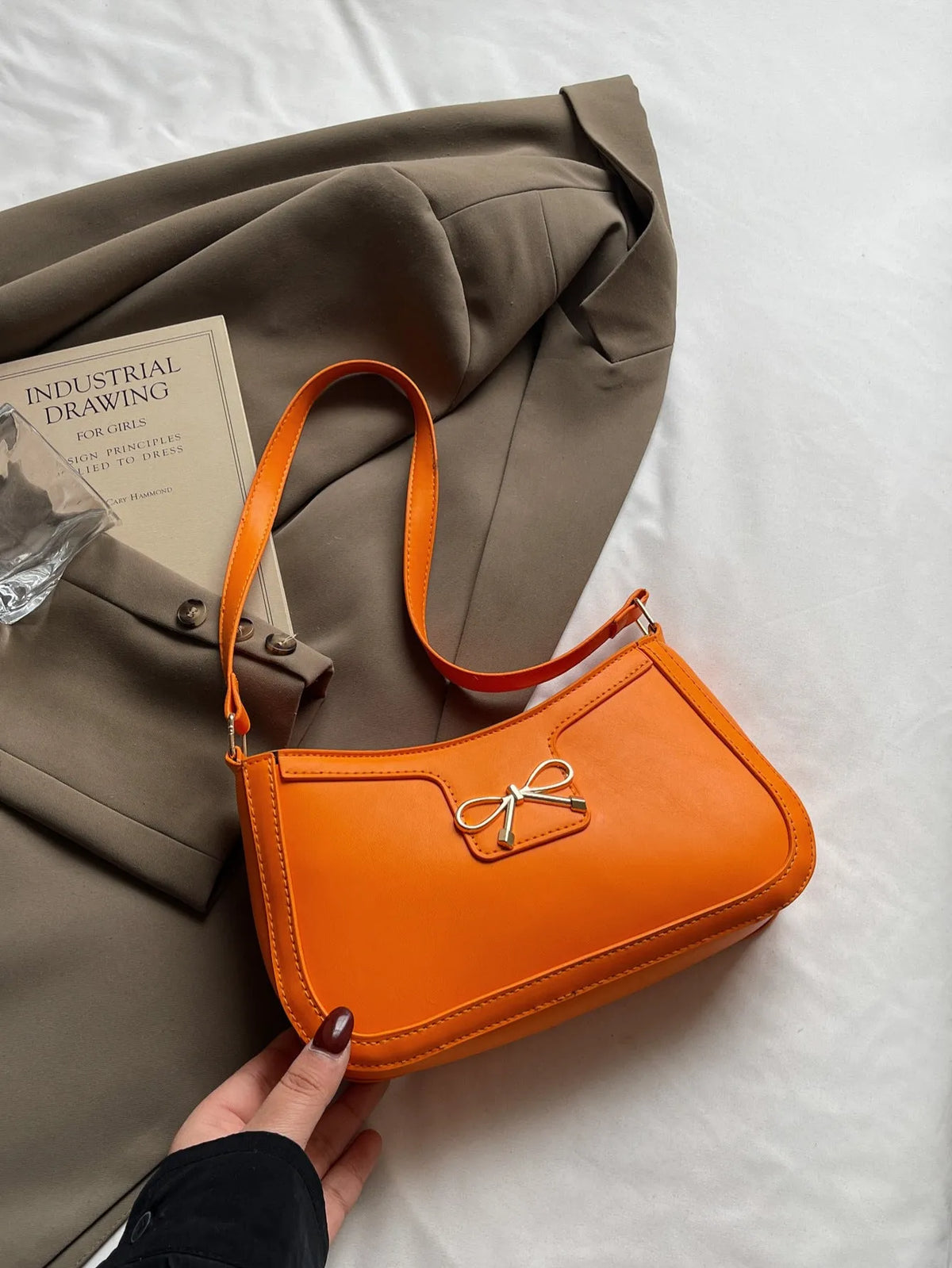 Western style shoulder bag with bow detail in rose pink colour, showing horizontal square shape and single strap.