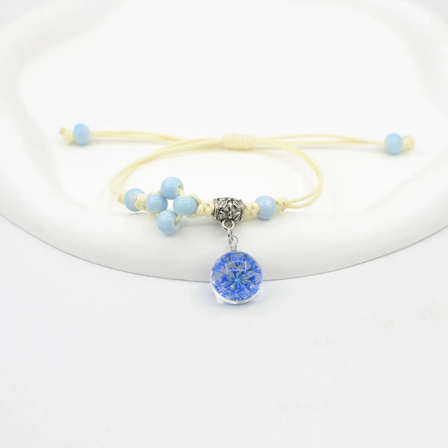 Hand-woven glass bracelet with large 1.4 cm beads containing real dried flowers, shown in blue.