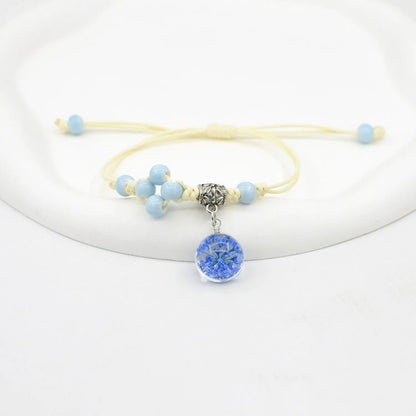 Hand-woven glass bracelet with large 1.4 cm beads containing real dried flowers, shown in blue.