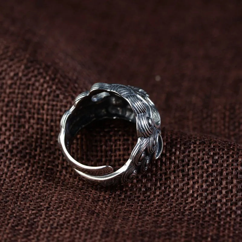 Silver open-style ring with a detailed raised jibeast animal pattern on a model's finger.