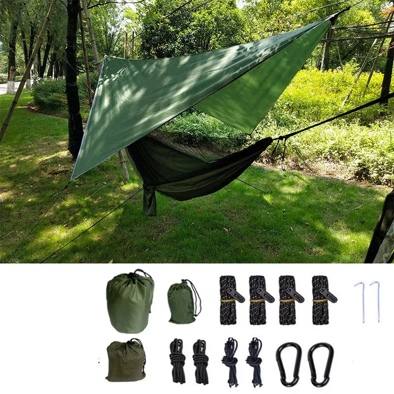 Portable camping hammock with mosquito net and awning setup in a forest