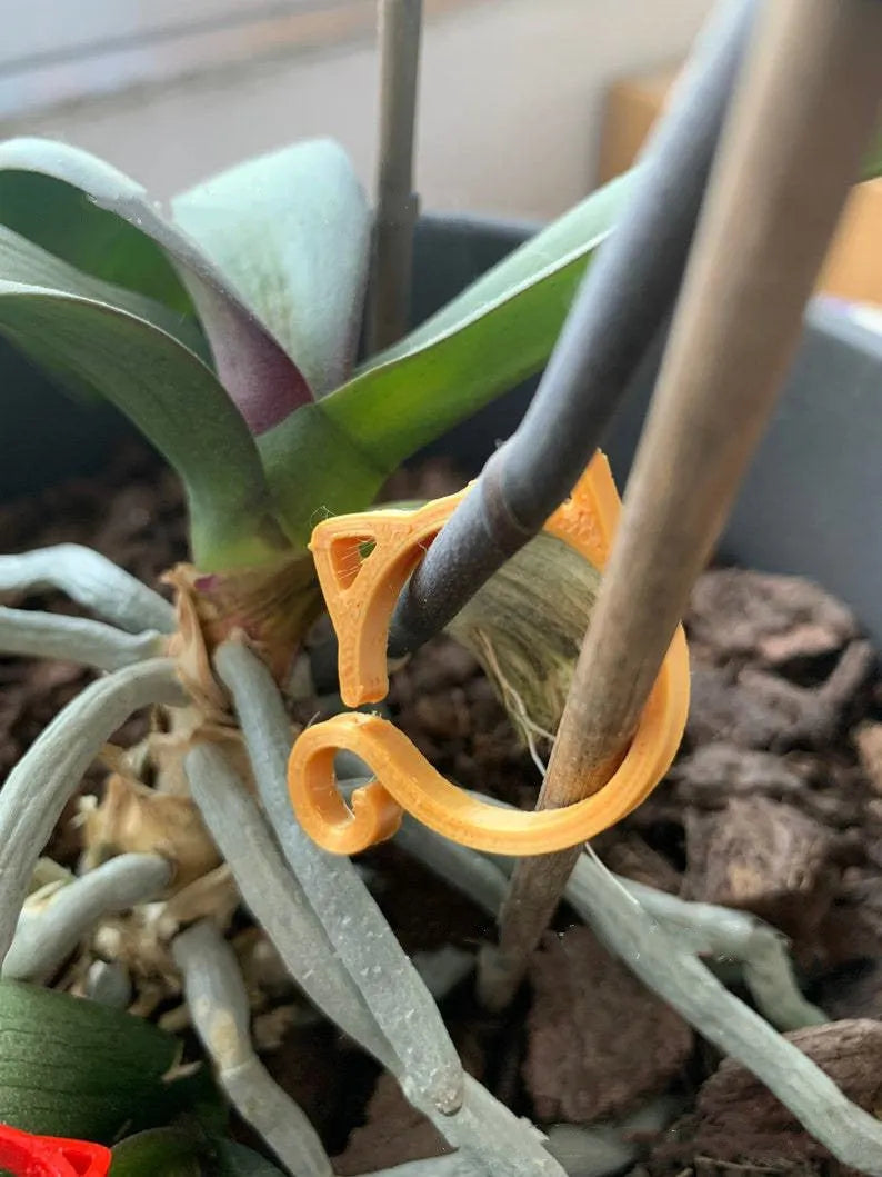 Red cat-shaped plastic gardening clip securing plant stem, showing 3cm length and decorative feline design