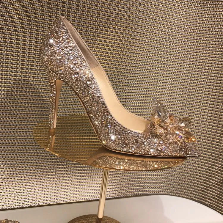 Women's gold pointed toe high heels with rhinestones and stiletto heel on a light background