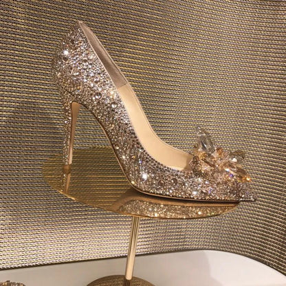 Women's gold pointed toe high heels with rhinestones and stiletto heel on a light background