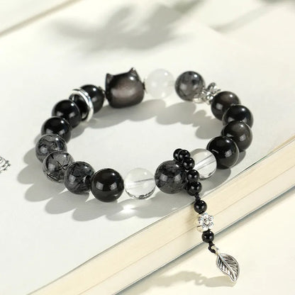 Silver stone crystal bracelet with diamond-shaped fox, cat head, and planet charms on white background.
