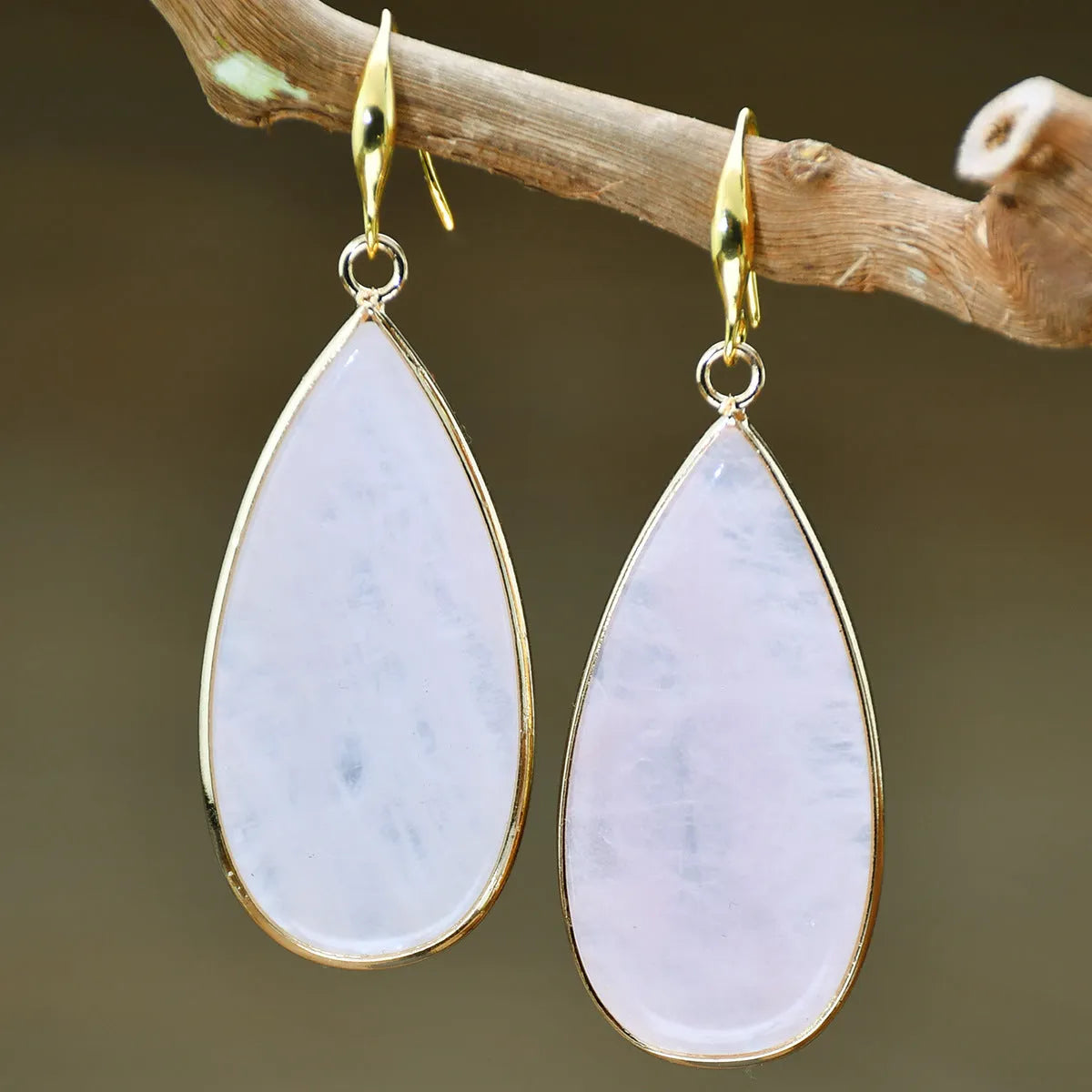 Close-up of long, polished tigereye stone drop earrings with a fishhook clasp on a neutral background.