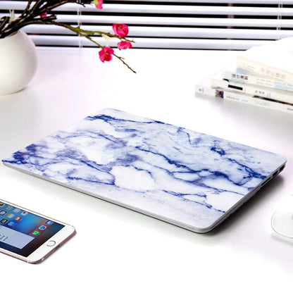 Plastic MacBook protective case in a marble pattern colour, shown next to a compatible Apple laptop.