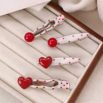 Red plastic hair clip with a 3D love heart and dots on a willow leaf-shaped base.