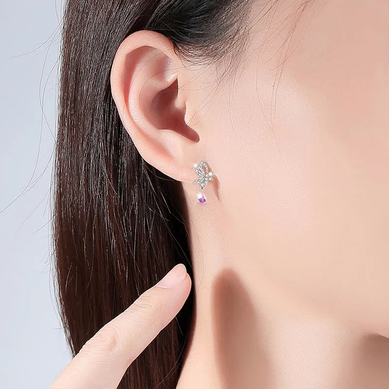 Butterfly shaped silver stud earrings with crystal details on white background